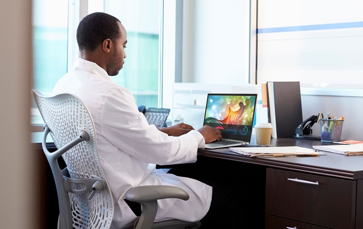 Dentist sitting at desk on computer