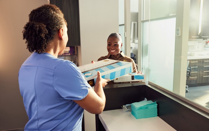 Office staff handing UPS driver a package