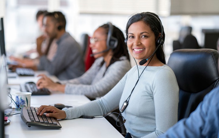 Row of people sitting at computers with headphones