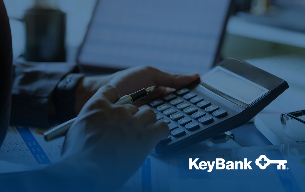 Hands working on calculator — KeyBank