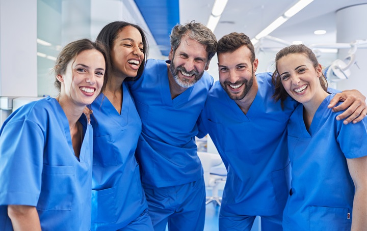 Group of  smiling students in blue scrubs.